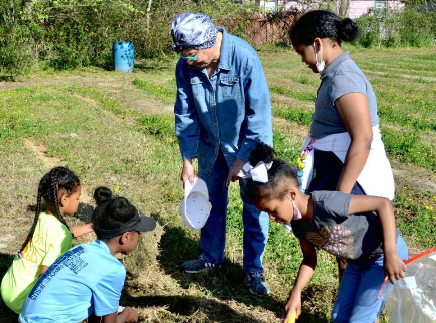 Neighborhood children gather around Eva Iford Friday as they examine the soil for the First Harvest Community Garden project.